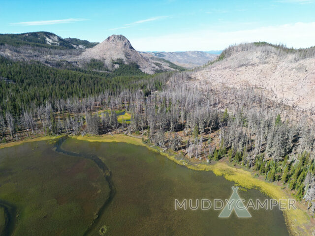 A butte that looks like a pyramid and a lake with a meadow