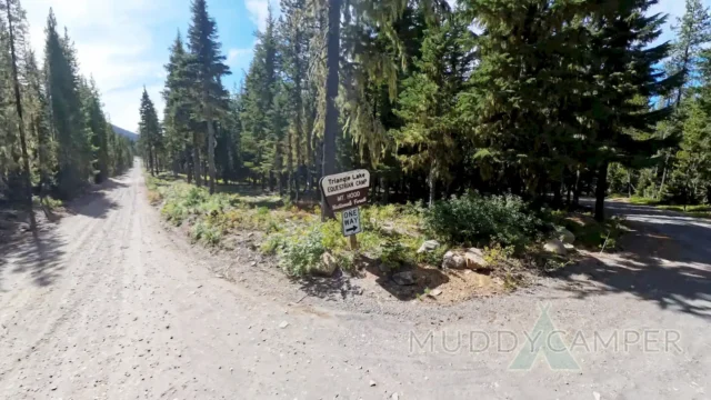 Sign of triangle lake in a forest and a gravel road